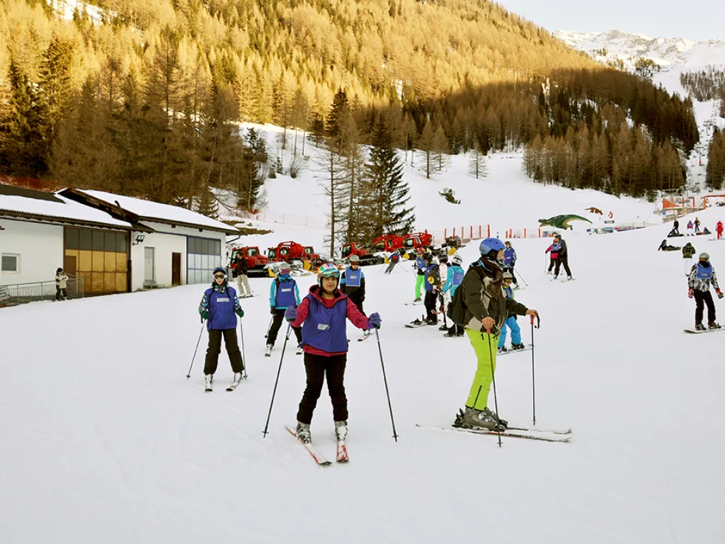 Skifahrende auf der Piste im warmen Abendlicht.
